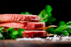 cru hamburguer em uma mesa com verduras e sal. foto