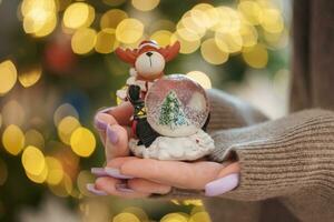 uma jovem menina com uma lindo luz roxa manicure é segurando uma neve globo foto