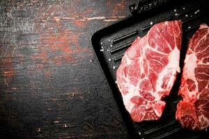 cru carne de porco bife em uma grade frigideira. foto