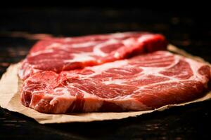 cru carne de porco bife em papel em a mesa. foto