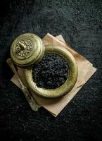 Preto caviar dentro velho tigela em papel. foto