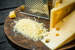 Grato queijo em uma de madeira borda. foto