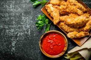 frango tiras com salsinha, francês fritas e tomate molho dentro tigela. foto