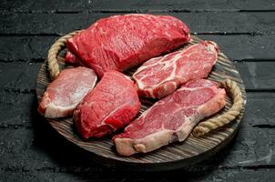 cru eu no. carne e carne de porco bifes em uma de madeira bandeja. foto