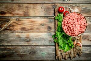 cru picado carne dentro uma tigela com salsinha, tomates e alho. foto