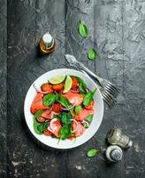 peixe salada. salada com fatias do salmão, tomates e espinafre com Lima suco. foto