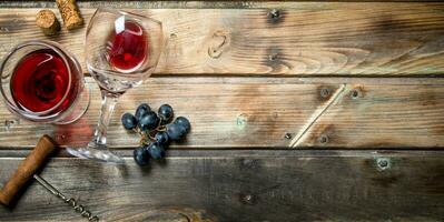 vermelho vinho dentro uma vidro com uvas e uma saca rolhas. foto