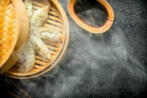 quente chinês tradicional gedza dumplings dentro bambu vaporizador com soja molho. foto