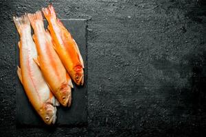 cru truta peixe em Preto pedra borda. foto