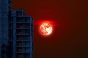 fundo de lua cheia de grão de sangue com prédio abandonado no céu noturno foto