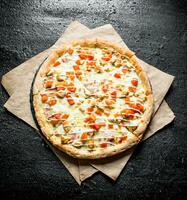 pizza com frango, tomates e queijo molho em papel. foto