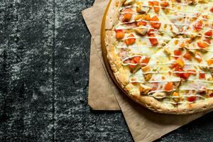 pizza com frango, tomates e queijo molho em papel. foto