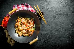 acabado udon Macarrão dentro uma wok panela com soja molho, pauzinhos e uma guardanapo. foto