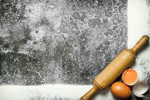 cozimento fundo. uma quadro, Armação do farinha com uma rolando PIN e fresco ovos. foto