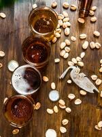 quatro cervejas com pistachios em uma de madeira mesa. foto