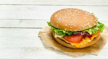 hamburguer com carne bovina, queijo e legumes em papel. foto