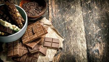 peças do uma diferente tipo do chocolate com aparas de madeira dentro uma tigela. foto