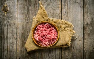 cru picado carne dentro uma de madeira tigela em velho tecido. foto