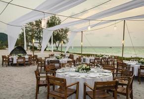 projeto de mesa de casamento romântico ao pôr do sol na praia tropical asiática em bali, Indonésia foto