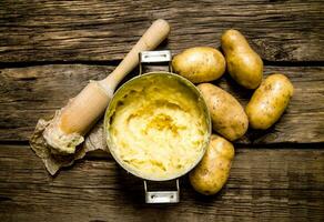 cozinhando amassado batatas com pilão em de madeira fundo. foto