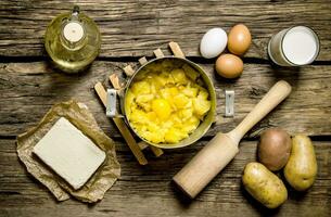 ingredientes para amassado batatas - ovos, leite, manteiga e batatas em de madeira fundo. foto