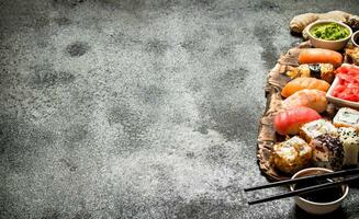 japonês Comida. Sushi e rolos fresco frutos do mar com soja molho e em conserva ruivo. em rústico fundo. foto
