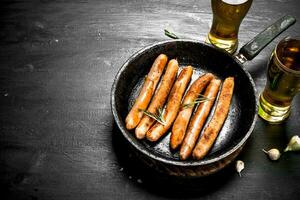 salsichas dentro uma fritar panela com uma vidro do cerveja. foto