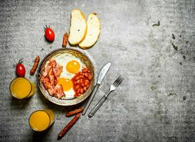 bacon, frito ovos com feijões e laranja suco. foto