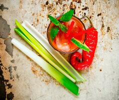 coquetéis fez do tomates, vodka, gelo, Lima, Pimenta , sal e lanche com salsão em rústico fundo . foto