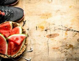 ginástica Comida. pedaços do Melancia com fones de ouvido e tênis. foto