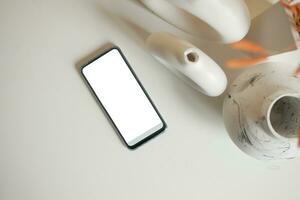 inteligente telefone com branco tela e casa interior decoração em mesa foto