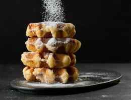 uma pilha do cozido Belga waffles borrifado com em pó açúcar foto