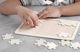 garotinho asiático brincando de quebra-cabeça de madeira foto