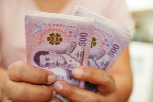 ásia mulher contando tailandês baht nota de banco dinheiro e segurando dentro mão, investimento economia, contabilidade o negócio e bancário. foto
