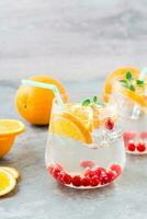 Difícil seltzer coquetel com laranja, oxicoco e hortelã dentro óculos em a mesa. alcoólico bebida. vertical Visão foto