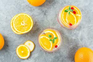 Difícil seltzer coquetel com laranja, oxicoco e hortelã dentro óculos em a mesa. alcoólico bebida. topo Visão foto
