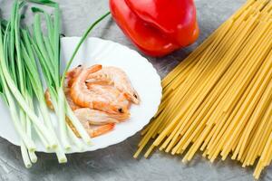 ingredientes para fazer udon e wok Macarrão com camarões, pimentas e cebolas em a mesa. chinês Comida foto