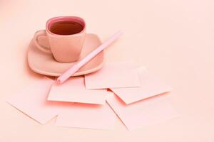 a conceito é Rosa. Rosa beber dentro uma café xícara, escrevendo folhas e caneta em uma Rosa fundo foto