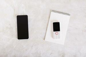 moderno Smartphone e botão de apertar telefone em bloco de anotações em mesa topo Visão foto