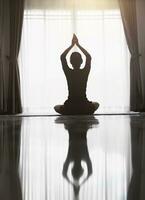 silhueta do mulher fazendo ioga às lar, meditação, ioga poses, esporte, pôr do sol. Esportes treinamento. foto