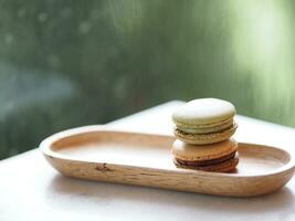 macaron sabor verde chá e café dentro de madeira bandeja prato forma elipse, sobremesa lanches tarde em mármore mesa borrado do natureza fundo, sobremesa lanches, doce Comida foto