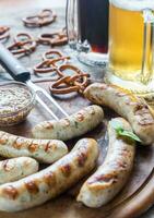 grelhado salsichas com salgadinhos e canecas do Cerveja foto