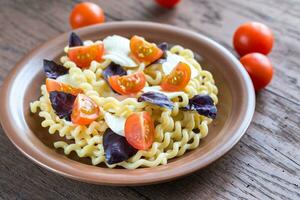 fusilli lunghi com queijo e tomate cereja foto