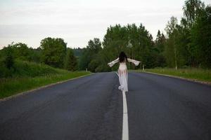 vista traseira de uma jovem em uma estrada de asfalto vazia foto