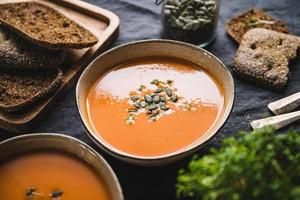 Sopa cremosa de vegetais saudável com sementes de abóbora na mesa da cozinha