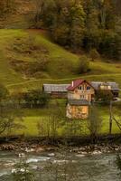 outono montanha panorama com amarelo Relva e rural de madeira casas. campo natureza foto