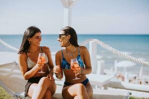 sorridente jovem mulheres dentro bikini desfrutando período de férias em a de praia foto