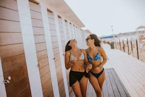 sorridente jovem mulheres dentro bikini desfrutando período de férias em a de praia foto