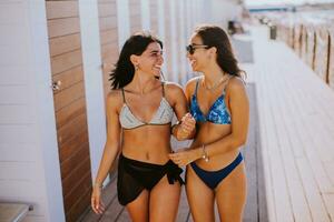 sorridente jovem mulheres dentro bikini desfrutando período de férias em a de praia foto