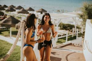 sorridente jovem mulheres dentro bikini desfrutando período de férias em a de praia foto